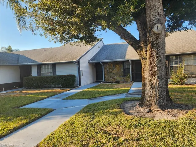 Ranch-style house with a front yard, stone siding, and roof with shingles