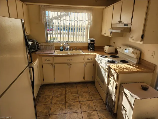 Kitchen featuring white appliances, light countertops, and dark tile patterned flooring