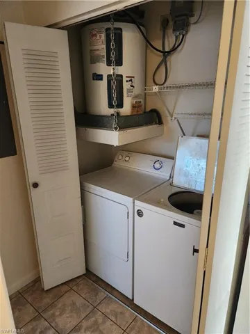 Laundry area featuring water heater and light tile patterned floors