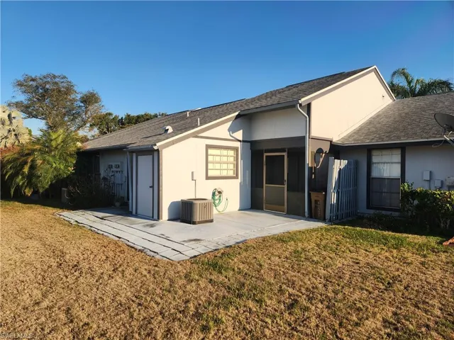 Rear view of house featuring a yard, a shingled roof, a sunroom, and a patio area