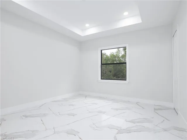 Empty room featuring light tile patterned flooring and a raised ceiling