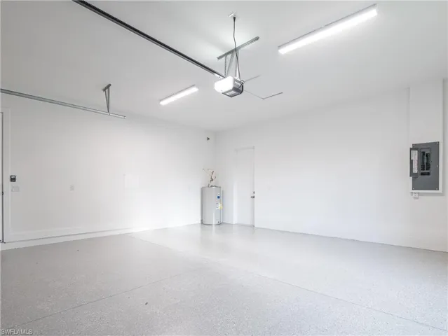 Garage with electric panel, a garage door opener, and water heater