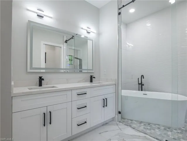 Bathroom featuring double sink vanity, a bath, and tile patterned flooring