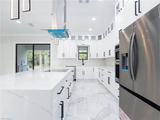 Kitchen featuring a healthy amount of sunlight, stainless steel appliances, island range hood, light tile patterned floors, and decorative backsplash