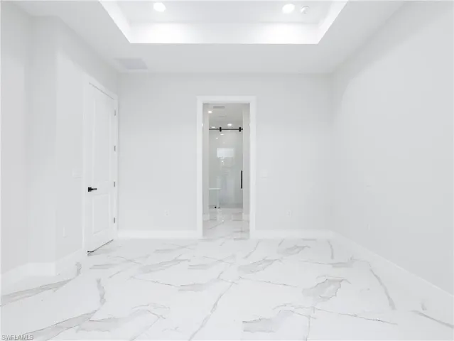 Tiled empty room featuring a raised ceiling