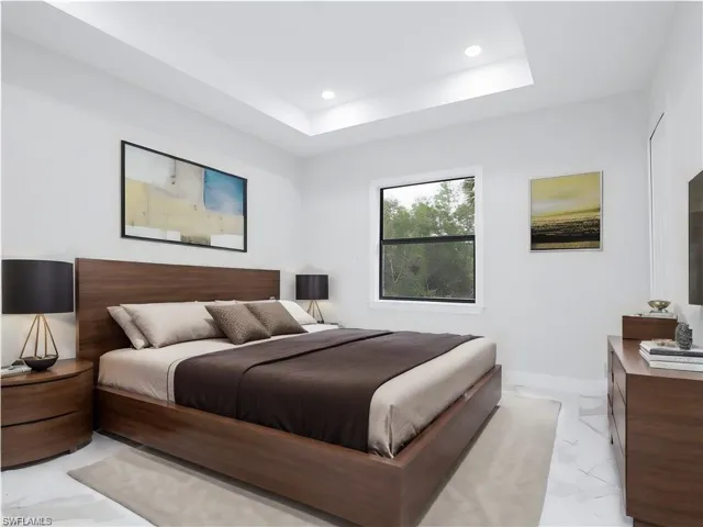 Bedroom featuring light tile patterned floors and a tray ceiling