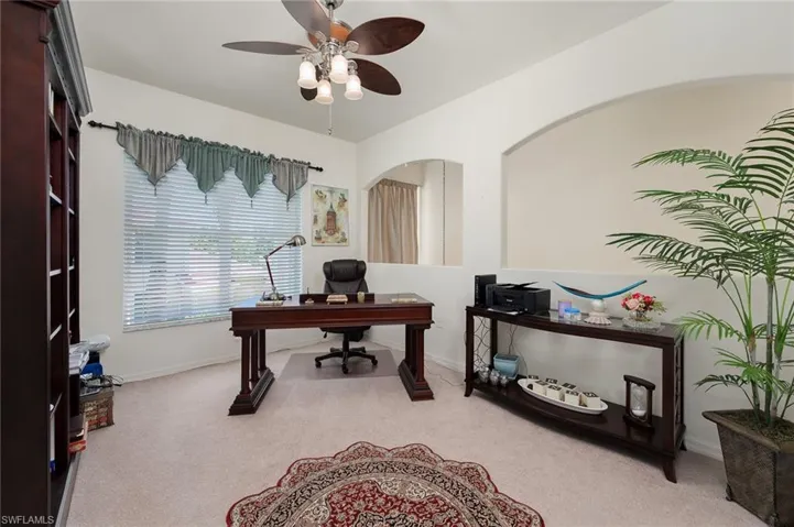 Office space with light carpet and ceiling fan