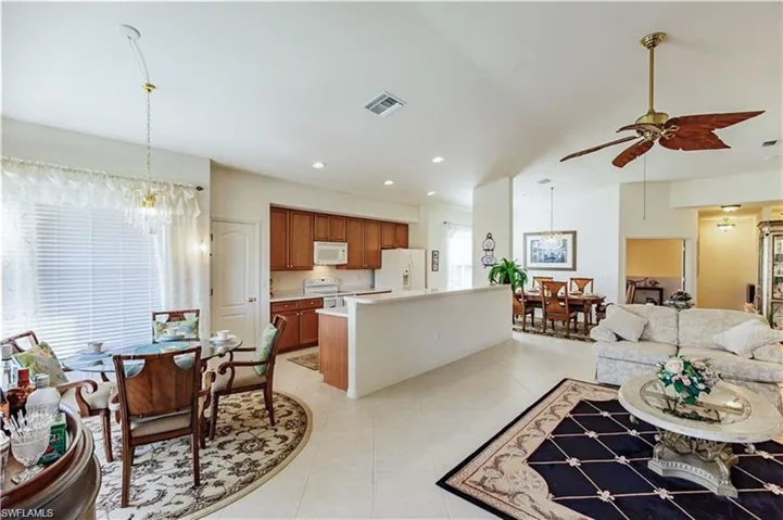 Living room featuring light tile floors and ceiling fan with notable chandelier