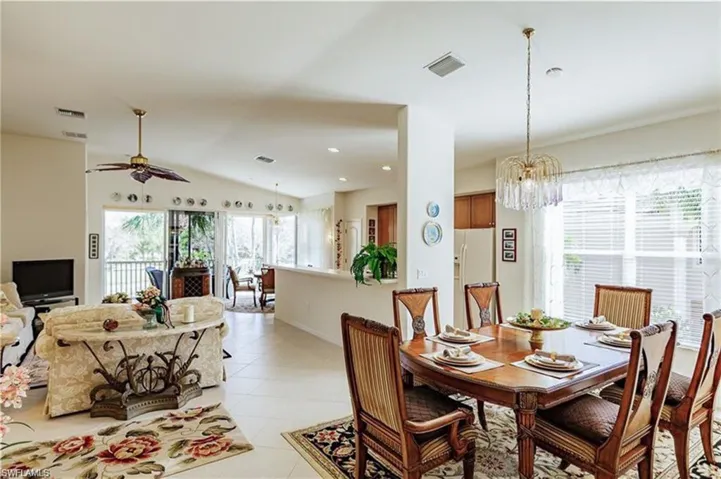 Tiled dining area featuring ceiling fan with notable chandelier and lofted ceiling