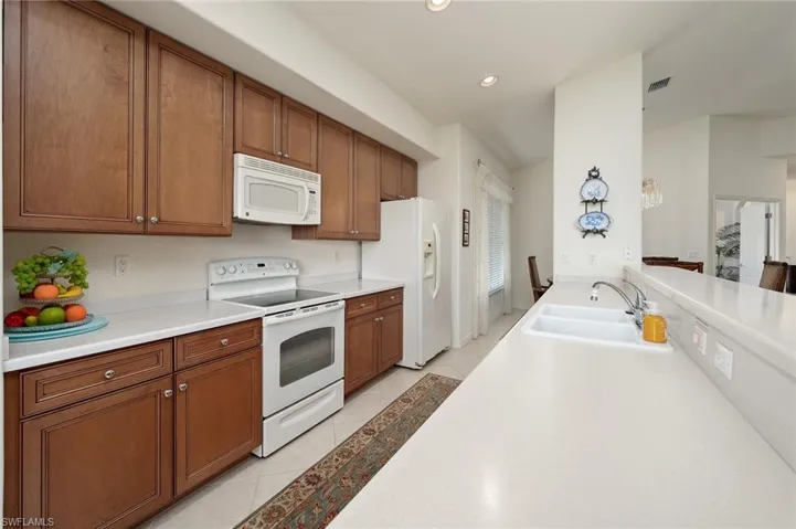 Kitchen with sink, white appliances, and light tile floors