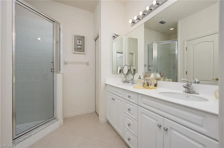 Bathroom with an enclosed shower, tile floors, large vanity, and double sink