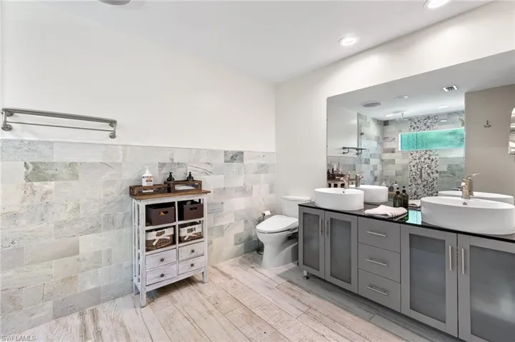 Bathroom featuring dual vanity, hardwood / wood-style flooring, toilet, and tile walls