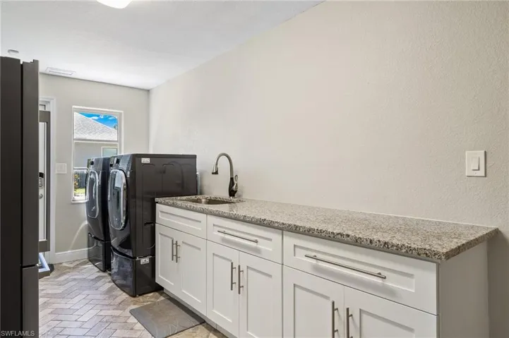 Washroom featuring washing machine and dryer, sink, and cabinets