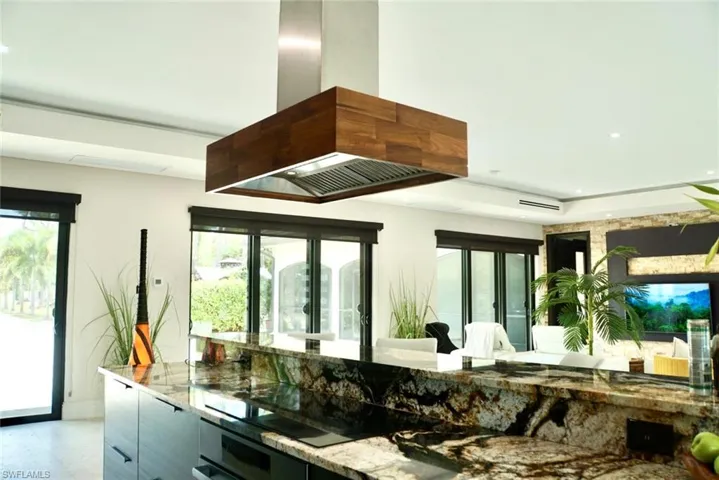 Kitchen featuring island range hood, black electric stovetop, stone countertops, and oven