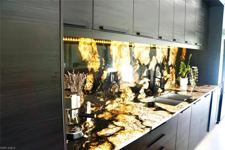 Details featuring gray cabinets, sink, and light stone countertops