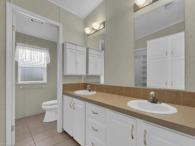 Bathroom with tile patterned flooring, vanity, toilet, and ornamental molding