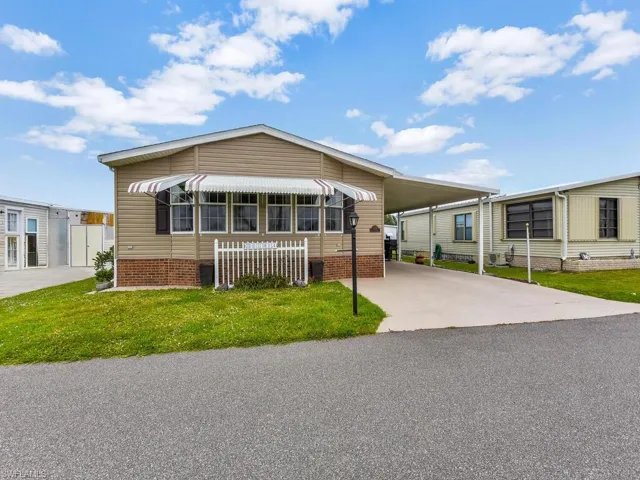 Manufactured / mobile home featuring a front lawn and a carport