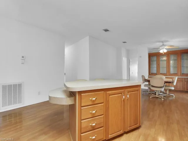 Kitchen featuring ceiling fan, a center island, a kitchen bar, and light hardwood / wood-style flooring
