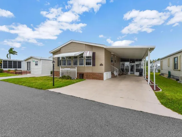Manufactured / mobile home featuring a front yard and a carport