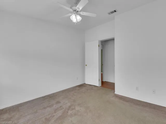 Carpeted empty room featuring ceiling fan