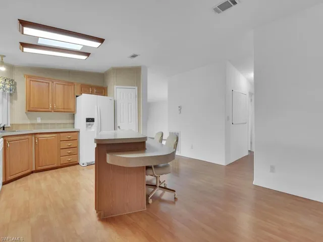 Kitchen with a kitchen bar, a kitchen island, white refrigerator with ice dispenser, and light wood-type flooring