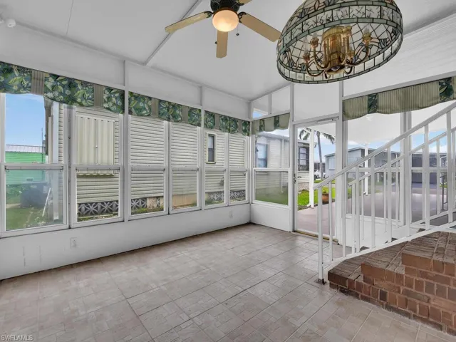 Unfurnished sunroom with ceiling fan with notable chandelier and plenty of natural light
