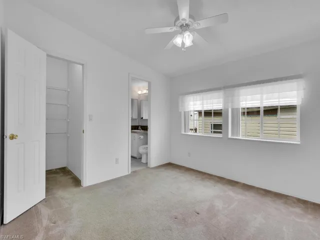 Unfurnished bedroom with a closet, ensuite bathroom, ceiling fan, and light colored carpet