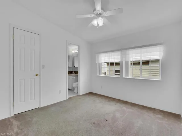 Unfurnished bedroom featuring ensuite bathroom, sink, ceiling fan, and light colored carpet