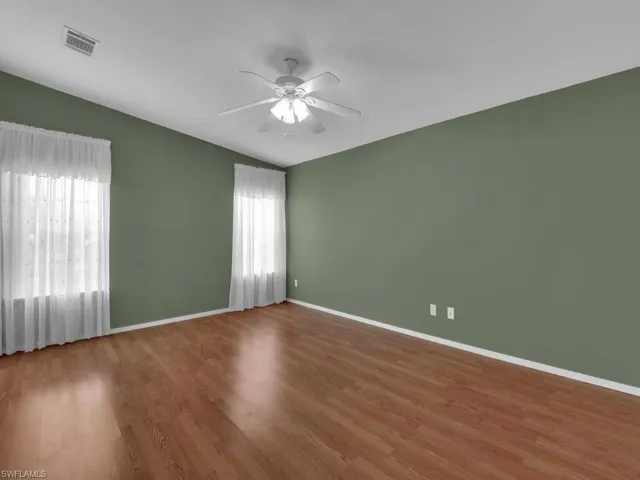 Empty room with hardwood / wood-style flooring, ceiling fan, and vaulted ceiling