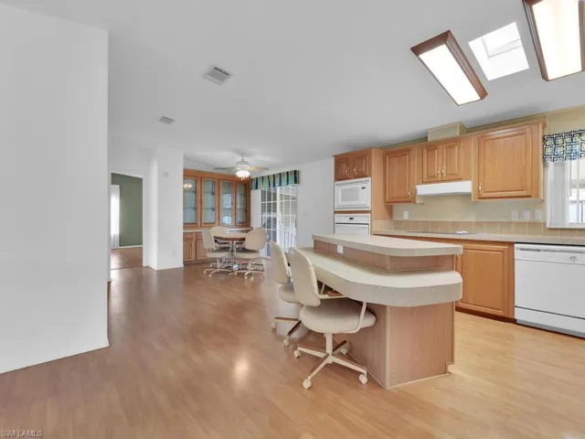 Kitchen featuring a center island, white appliances, a skylight, light hardwood / wood-style flooring, and ceiling fan