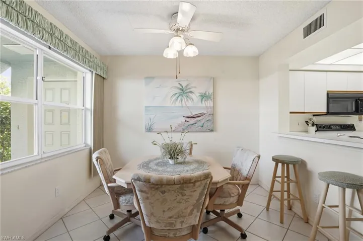 Dining room featuring a ceiling fan, a textured ceiling, and light tile patterned floors