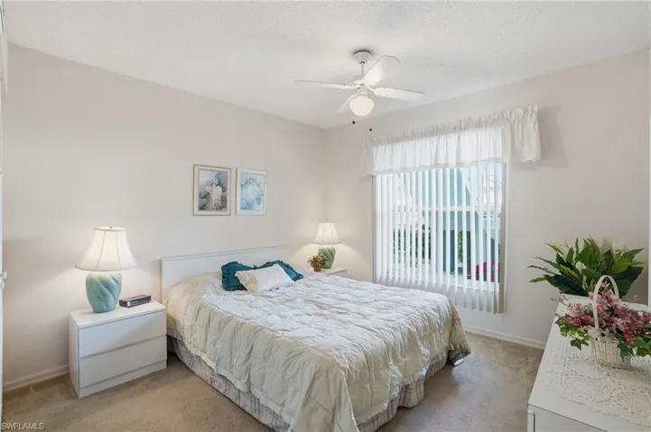 Bedroom with a textured ceiling, light carpet, and ceiling fan