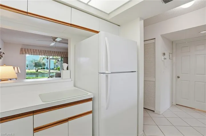 Two tone kitchen with freestanding refrigerator, light countertops, two tone color scheme, a textured ceiling, and ceiling fan