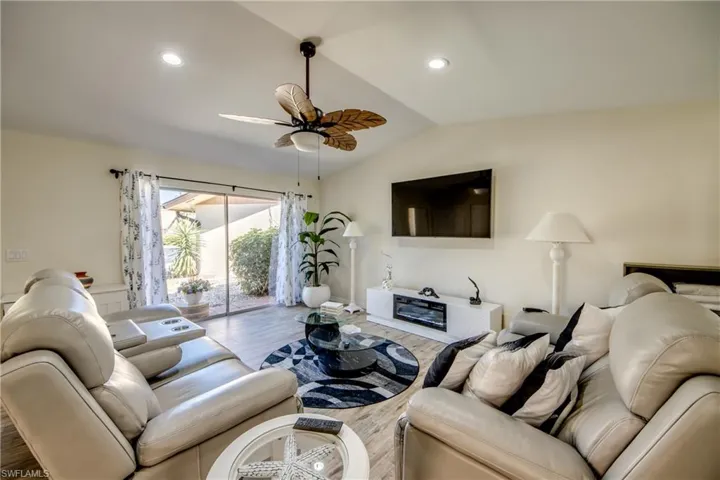 Living area featuring wood finished floors, a ceiling fan, lofted ceiling, and recessed lighting