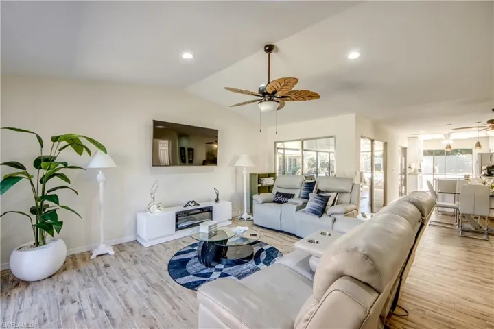 Living room with light wood-type flooring, recessed lighting, vaulted ceiling, and ceiling fan