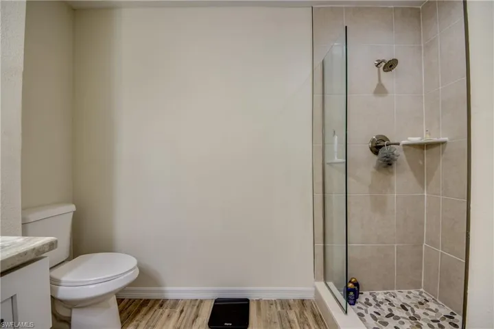 Bathroom featuring a shower stall, vanity, and wood finished floors