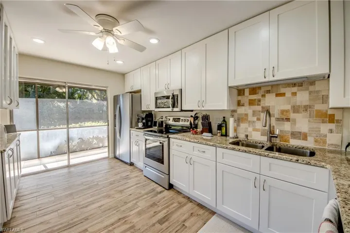 Kitchen featuring stainless steel appliances, white cabinetry, light stone counters, recessed lighting, and tasteful backsplash