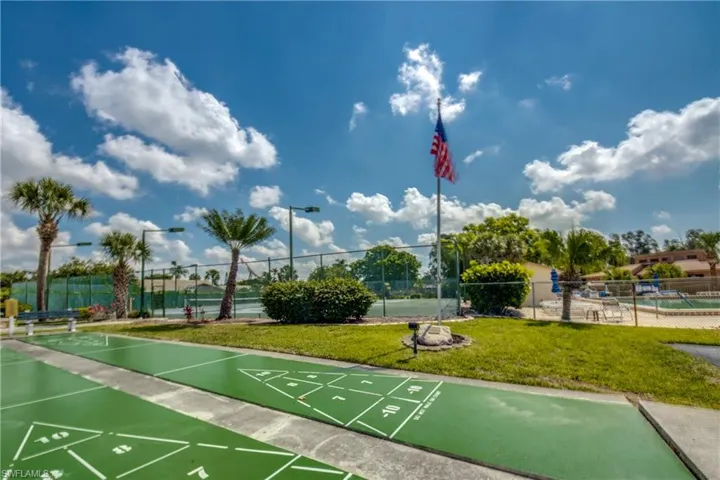 View of community with shuffleboard and a tennis court