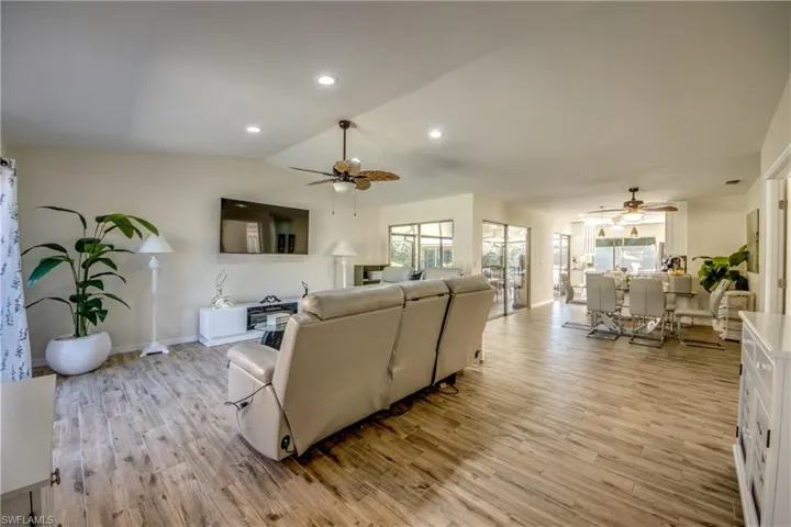 Living area with light wood-style flooring, lofted ceiling, recessed lighting, and ceiling fan