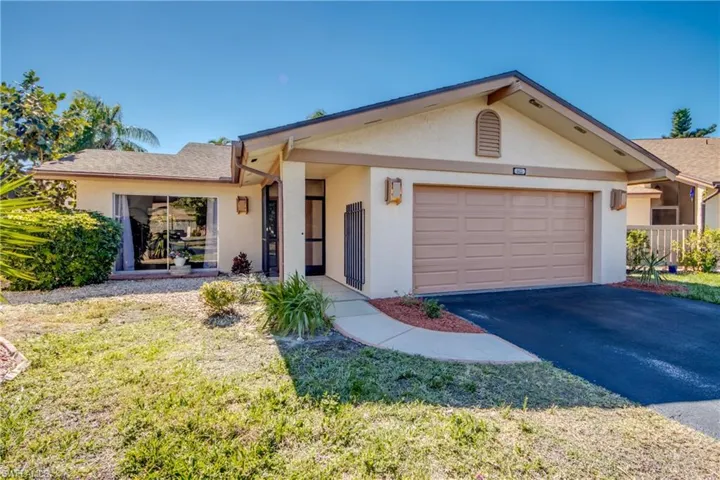 Ranch-style home with stucco siding, a front lawn, driveway, and a garage