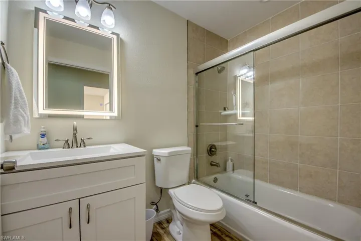 Bathroom featuring shower / bath combination with glass door, vanity, and a textured wall