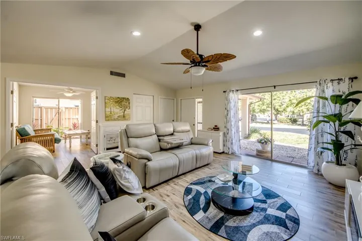 Living area with wood finished floors, ceiling fan, vaulted ceiling, and recessed lighting