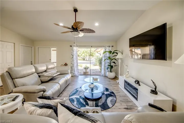 Living room featuring wood finished floors, vaulted ceiling, a ceiling fan, and recessed lighting