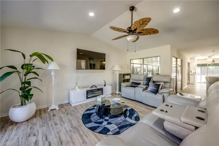 Living room featuring light wood finished floors, vaulted ceiling, recessed lighting, and ceiling fan