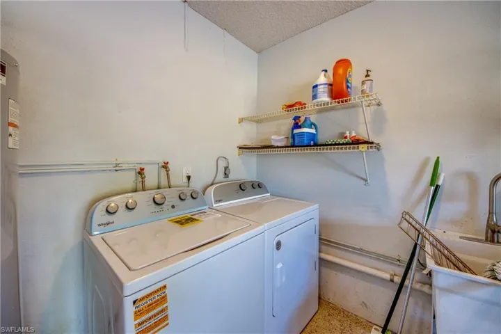 Laundry room featuring separate washer and dryer, a textured ceiling, and water heater