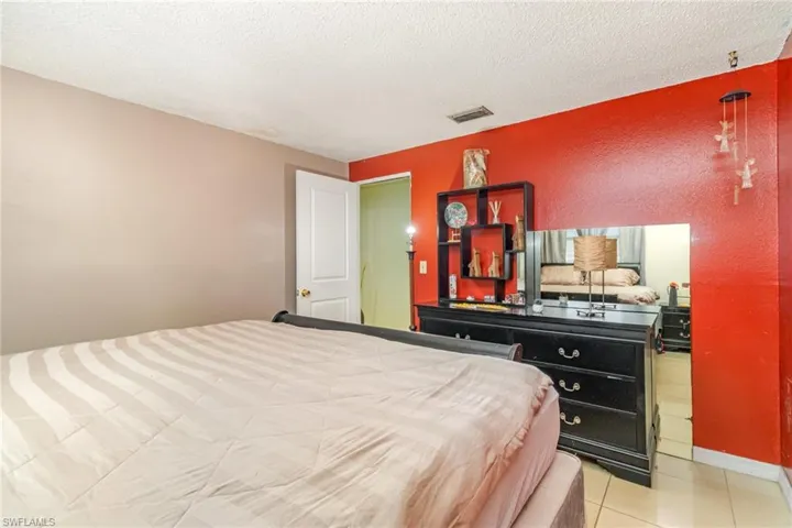 Bedroom with a textured ceiling, light tile patterned flooring, and a textured wall