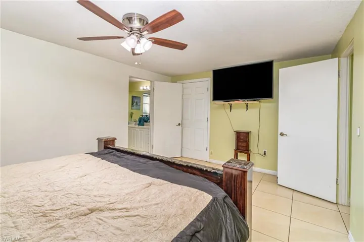 Bedroom featuring tile patterned floors, a ceiling fan, a closet, and connected bathroom