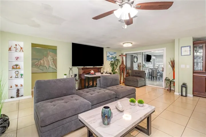 Living room with light tile patterned floors and a ceiling fan