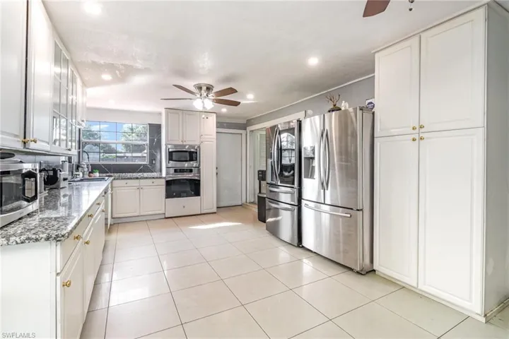 Kitchen featuring appliances with stainless steel finishes, a ceiling fan, light tile patterned floors, white cabinets, and recessed lighting