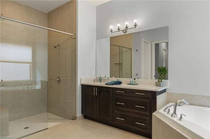 Bathroom featuring vanity, shower with separate bathtub, and tile patterned flooring